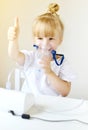 Little girl in a mask for inhalations, making inhalation with nebulizer at home inhaler on the table Royalty Free Stock Photo