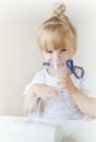 Little girl in a mask for inhalations, making inhalation with nebulizer at home inhaler on the table Royalty Free Stock Photo