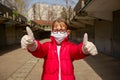 Little girl in medical mask and gloves is showing thumbs up