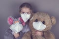 Little girl in a medical mask hugs a soft toys