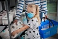 Girl with medical mask and mother buying toilet paper in shop