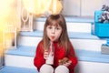 Little girl with milk and a gingerbread man sitting on porch near house. child eats cookies with milk on porch at home. Child with Royalty Free Stock Photo