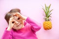 Little girl and mini pineapple on a pink background Royalty Free Stock Photo