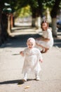 Little girl with mom in a beautiful white dress, smiles and runs in a green park, picnic Royalty Free Stock Photo