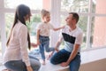 Little girl with mom and dad sits by the big window in studio. Family photosession Royalty Free Stock Photo