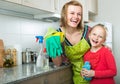 Little girl and mom tidy up at kitchen Royalty Free Stock Photo