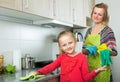 Little girl and mom tidy up at kitchen. Royalty Free Stock Photo