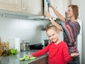 Little girl and mom tidy up at kitchen Royalty Free Stock Photo