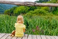 Little girl with monkey sits on wooden walkway and dreams. Tourism. Active family time in nature. Hiking with small children