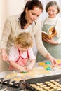 Little girl with mother cutting out cookies