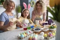 Little girl with mother and grandmother dyeing Easter eggs
