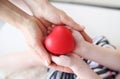 Little girl and mother hands holding red toy heart closeup Royalty Free Stock Photo