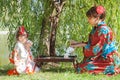 Little girl with mother in kimono sitting beside the tea table Royalty Free Stock Photo