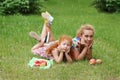 Little girl and mother lie on lawn in green summ