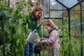 Little girl and mother watering plants in garden, using collected rainwater. Concept of water conservation in garden and