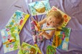 A little girl with multi-colored pencils in her hands on the floor among many of her drawings. Royalty Free Stock Photo