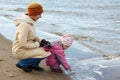 Little girl with mum walk on autumn beach