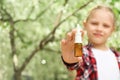 Little girl with nasal drops near blooming tree. Allergy concept Royalty Free Stock Photo