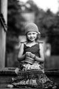 Little girl in national dress sitting outdoor in the village. Black and white photo. Royalty Free Stock Photo