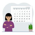 Little girl near the big calendar. Plans things for the month, study, holidays, weekends and important dates.