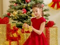Little girl near the Christmas tree is holding ornaments. Royalty Free Stock Photo