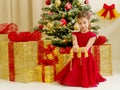Little girl near the Christmas tree is holding ornaments. Royalty Free Stock Photo