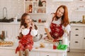 A little girl in the New Year& x27;s kitchen is sitting on the table with cookies in her hands eating it, and her mother is Royalty Free Stock Photo