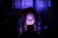 A little happy girl at night looks at the smartphone under a blanket in her bed. Royalty Free Stock Photo