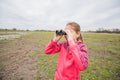 Little girl observing with binoculars nature landscape on spring day Royalty Free Stock Photo