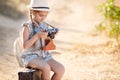 A little girl with an old camera on a country road sitting on a suitcase Royalty Free Stock Photo