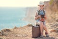 A little girl with an old camera on a country road sitting on a suitcase Royalty Free Stock Photo