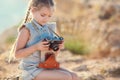 A little girl with an old camera on a country road sitting on a suitcase Royalty Free Stock Photo