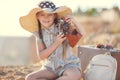 A little girl with an old camera on a country road sitting on a suitcase Royalty Free Stock Photo