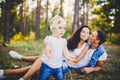 Little girl one year on the background of parents resting lying on grass learning to walk on nature in the park. The first steps o Royalty Free Stock Photo