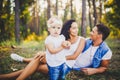 Little girl one year on the background of parents resting lying on grass learning to walk on nature in the park. The first steps Royalty Free Stock Photo