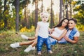 Little girl one year on the background of parents resting lying on grass learning to walk on nature in the park. The first steps Royalty Free Stock Photo