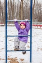Little girl one year old climbing the ladder outside in winter park playground.