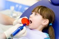 little girl with open mouth receiving dental filling drying procedure.