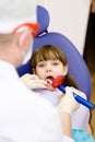 little girl with open mouth receiving dental filling drying procedure.
