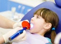 little girl with open mouth receiving dental filling drying procedure.