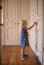 Little girl opening cabinet door in dressing room of large home Royalty Free Stock Photo