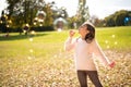 Little girl outdoors at beautiful autumn day blows soap bubbles Royalty Free Stock Photo