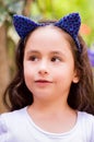 Little girl at outdoors on a summer nature, wearing a blue ears tiger accessories over her head in a blurred nature Royalty Free Stock Photo