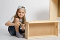 Little girl in overalls collector collects furniture drawer of the dresser