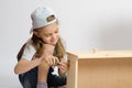 Little girl in overalls collector of furniture screws screwdriver