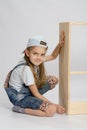 Little girl in overalls collector of furniture turn on dresser