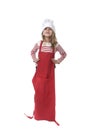 Little girl in oversized cooking hat and red apron playing cook smiling happy and playful