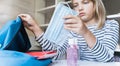 Little girl packing blue backpack in kids`s room. Face mask, bottle of sanitizer, stationery, pens, multicolored markers,