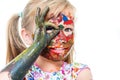 Little girl with painted face peeping through finger hole. Royalty Free Stock Photo