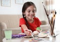 Little girl painting decorative egg at table. Creative hobby